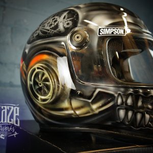 Custom painted black motorcycle helmet featuring detailed steampunk skull design with mechanical gears, bronze and orange airbrushed artwork on glossy finish